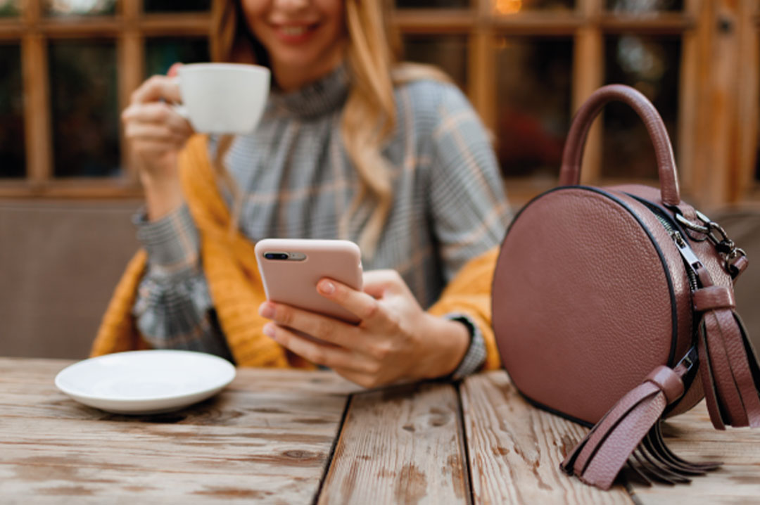 ragazza seduta a un bar con la borsa sul tavolo