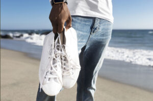 close up delle mani di un ragazzo che tengono delle sneakers bianche