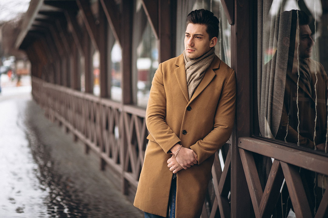 uomo con cappotto appoggiato alla ringhiera