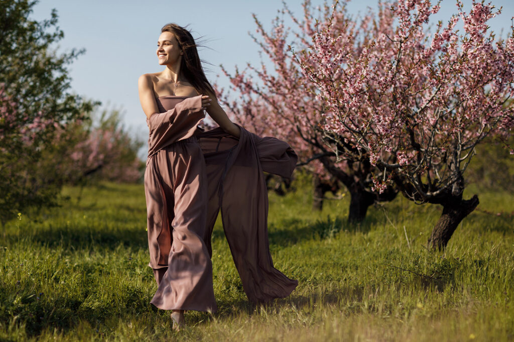 ragazza che passeggia in un prato con gli alberi di ciliegio in fiore