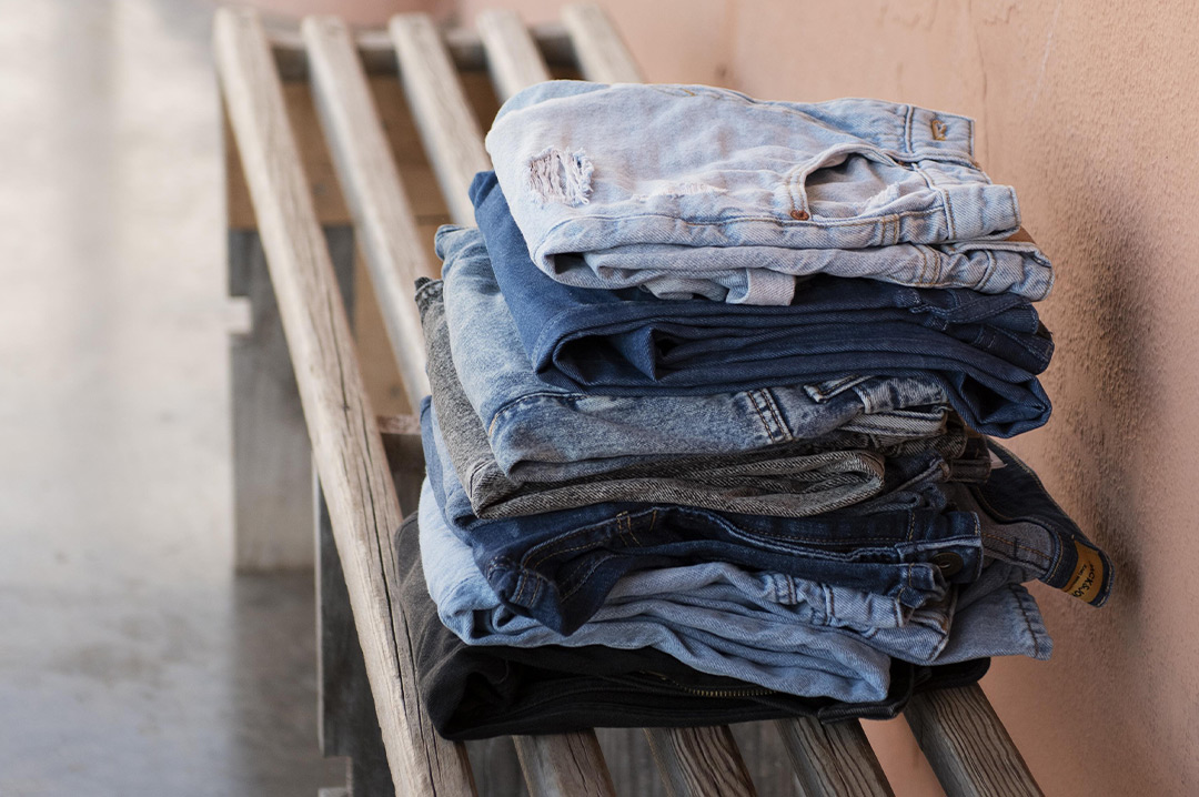 pila di jeans sistemati su una panchina all'aria aperta