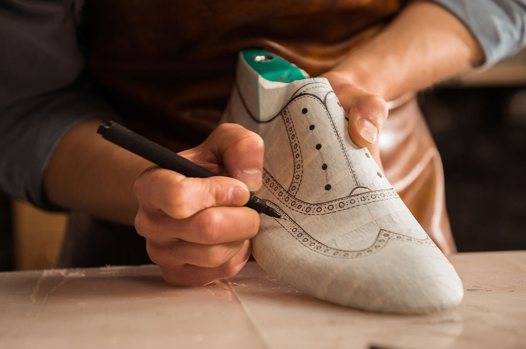 mani di un calzolaio che sistemano una scarpa in pelle
