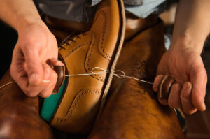 calzolaio che cuce delle scarpe in pelle